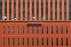 Orange facade of the Seoul Square building with South Korean and other international flags above its name